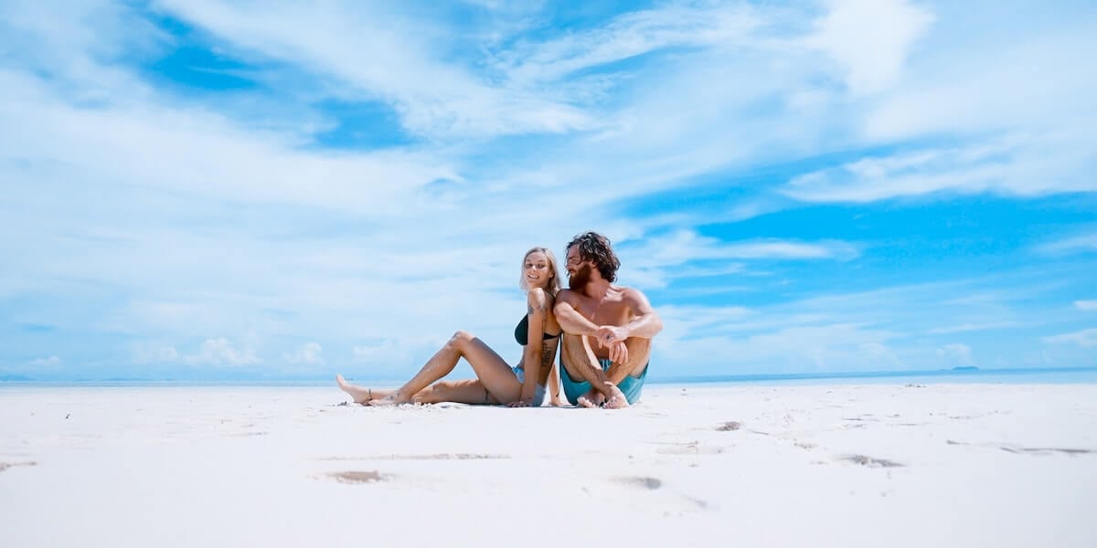 man and woman sitting on beach