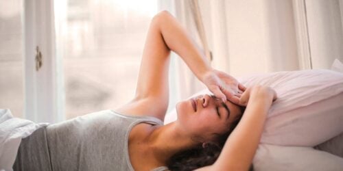 woman in bed experiencing headache