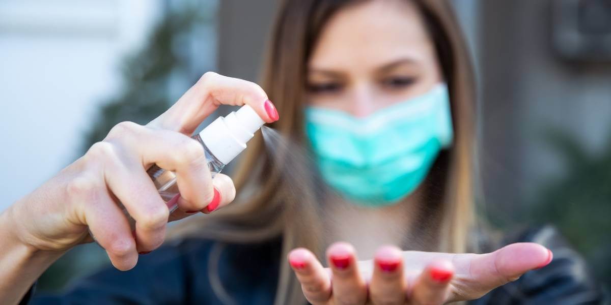 woman spraying hand sanitizer