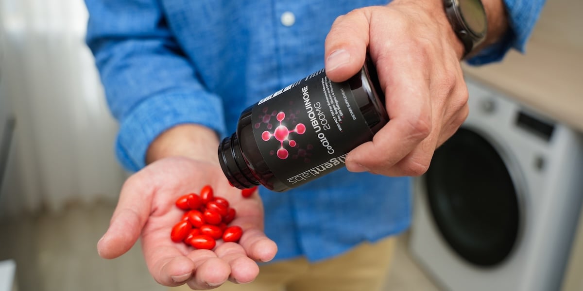 man holding bottle of coq10 ubiquinone from intelligent labs and pouring softgels into hand